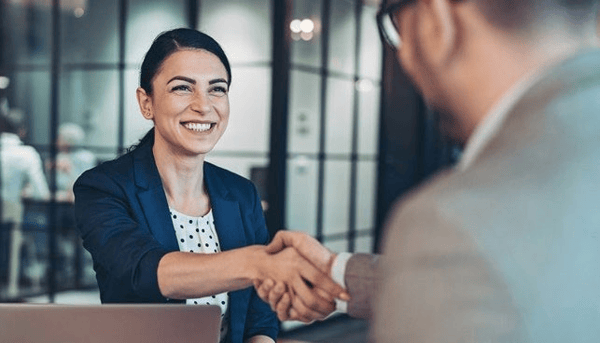 Woman shaking hands with someone else and smiling