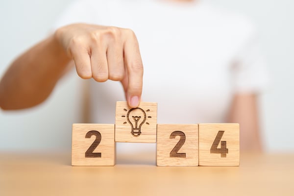 Man placing a building block with a lightbulb in place of the 0 in 2024