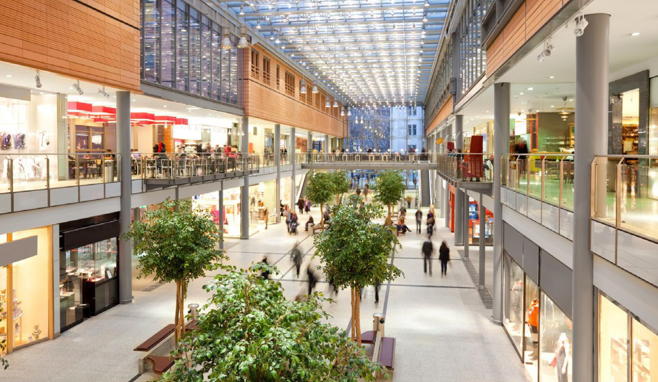 Image of two-story, indoor shopping mall with trees too