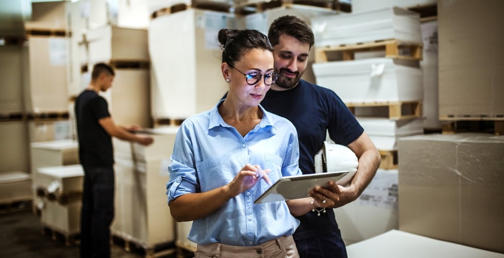 Woman and man in warehouse around boxes on tablet computer Woman and man in warehouse around boxes on tablet computer