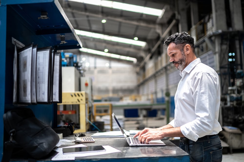 Business man in warehouse on laptop computer