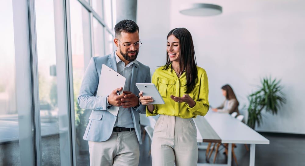 Male and female co-worker smiling and walking together in office Male and female co-worker smiling and walking together in office