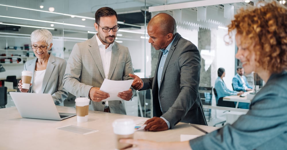 Men and women sitting and standing around a conference table in an office